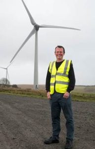  Dan McCallum smiling with a wind turbine behind him